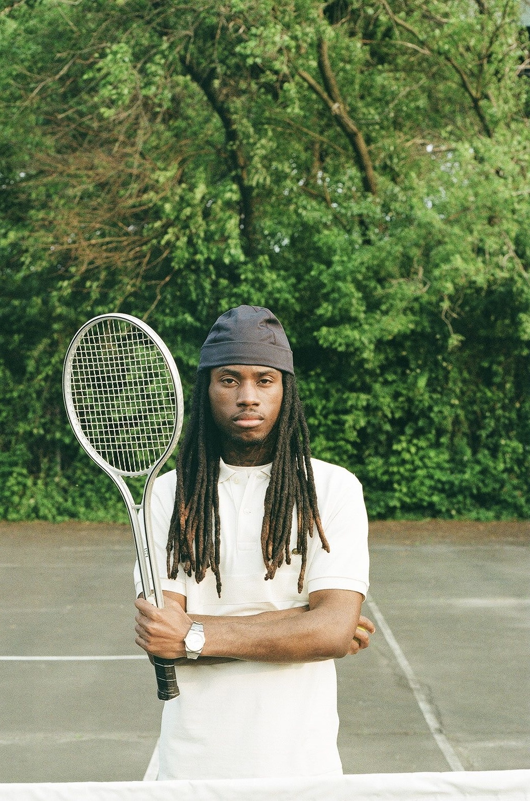 Diamon Logan holding a vintage tennis racket on a tennis court